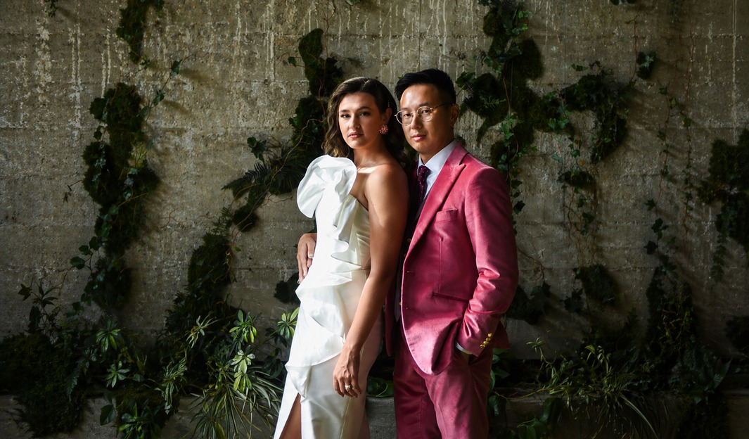 Bride and groom posed against a moss-covered concrete wall